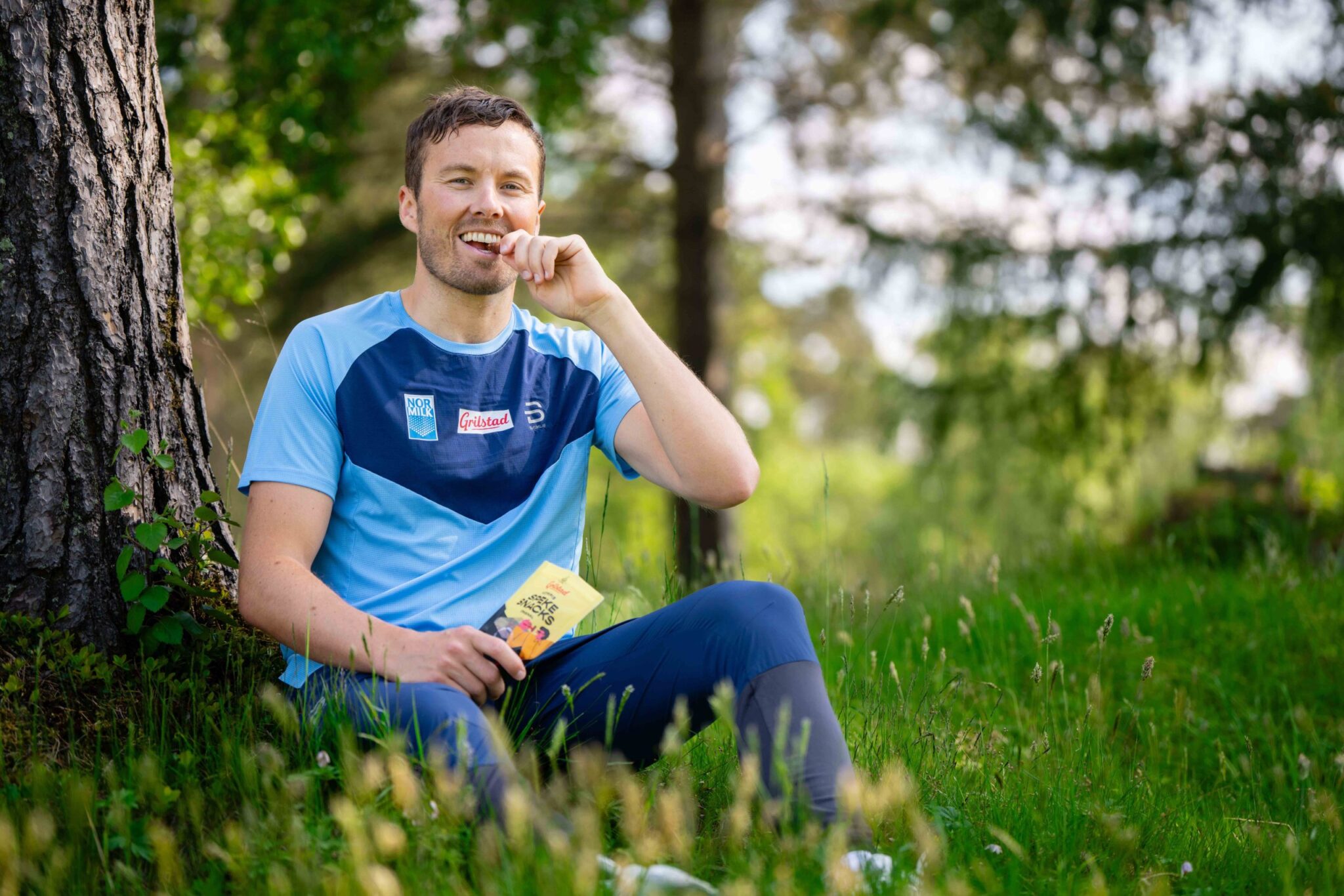 Emil Iversen tar en bit av en Grilstad-snack i skogen